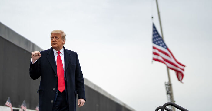 Donald Trump raising fist near wall with American flag, related to National Guard control amid protests in L.A.