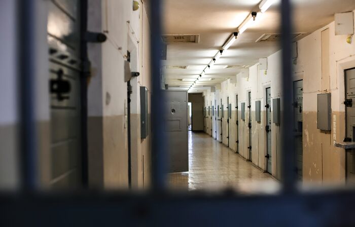 Prison hallway with closed cell doors, symbolizing man charged with sexually abusing daughter for 12 years case.