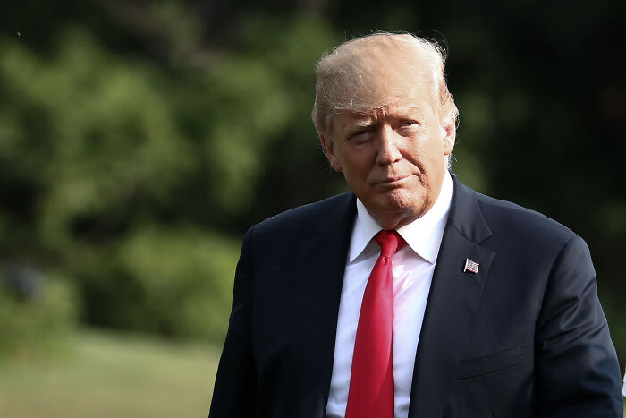 Donald Trump outdoors in a dark suit and red tie, linked to discussion of possible pardon for Ghislaine Maxwell. Donald Trump outdoors in a dark suit and red tie, linked to discussion of possible pardon for Ghislaine Maxwell.