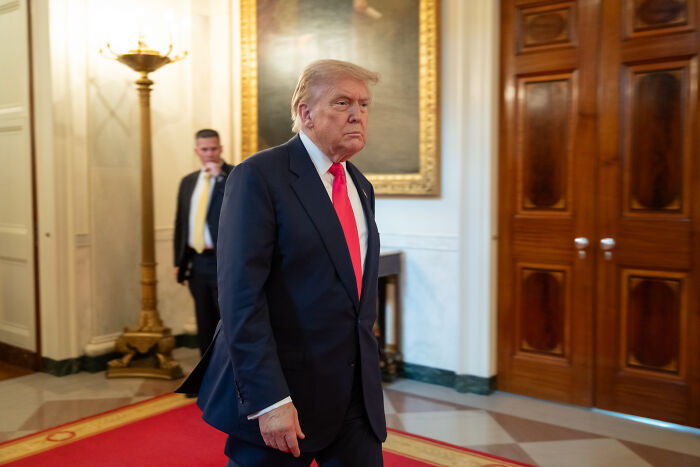 Former President Donald Trump walking in a formal setting, relates to swing-vote Murkowski’s decisive yes on GOP bill.