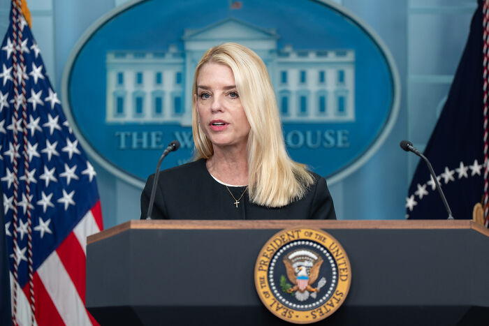 Senior advisor speaking at White House podium with presidential seal, related to Epstein client list discussion.