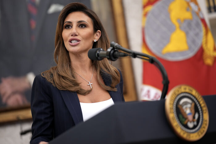 Woman speaking at a podium with presidential seal, discussing topics related to Trump senior advisor and Epstein client list.