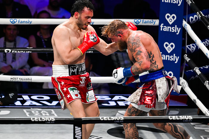 Two boxers in action inside the ring during a match, highlighting boxing champion and related cartel gun case.