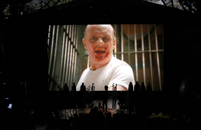 Scene from Hannibal movie projected on screen with audience silhouettes, highlighting Hannibal and cannibal themes.