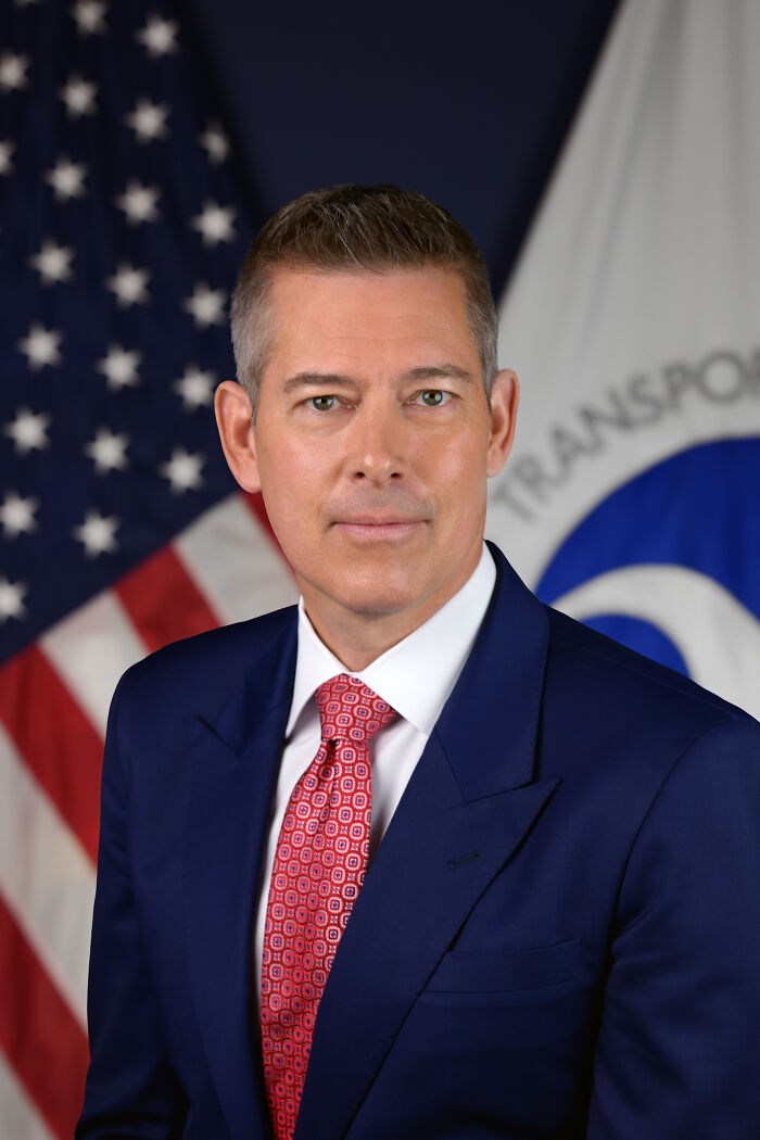 Professional portrait of a man in a suit with American flag, representing Trump's new NASA boss and MTV reality star.