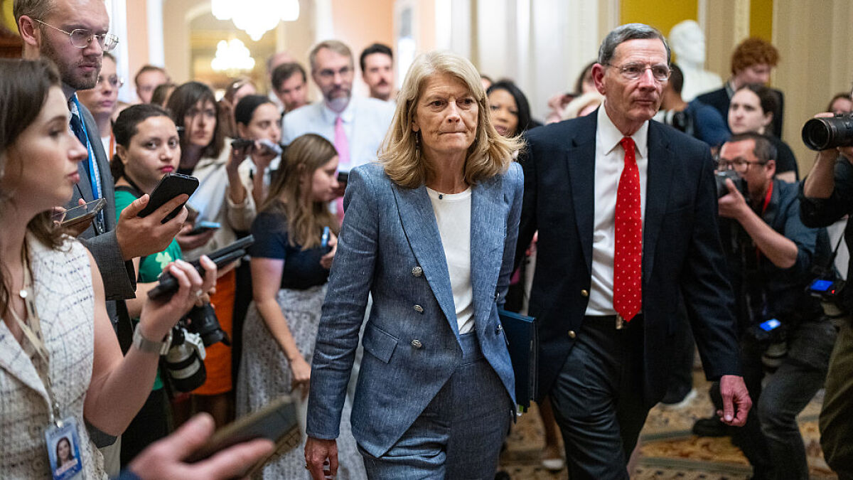 Senator Murkowski walking through a crowd of reporters and photographers after casting a swing-vote on a GOP bill.