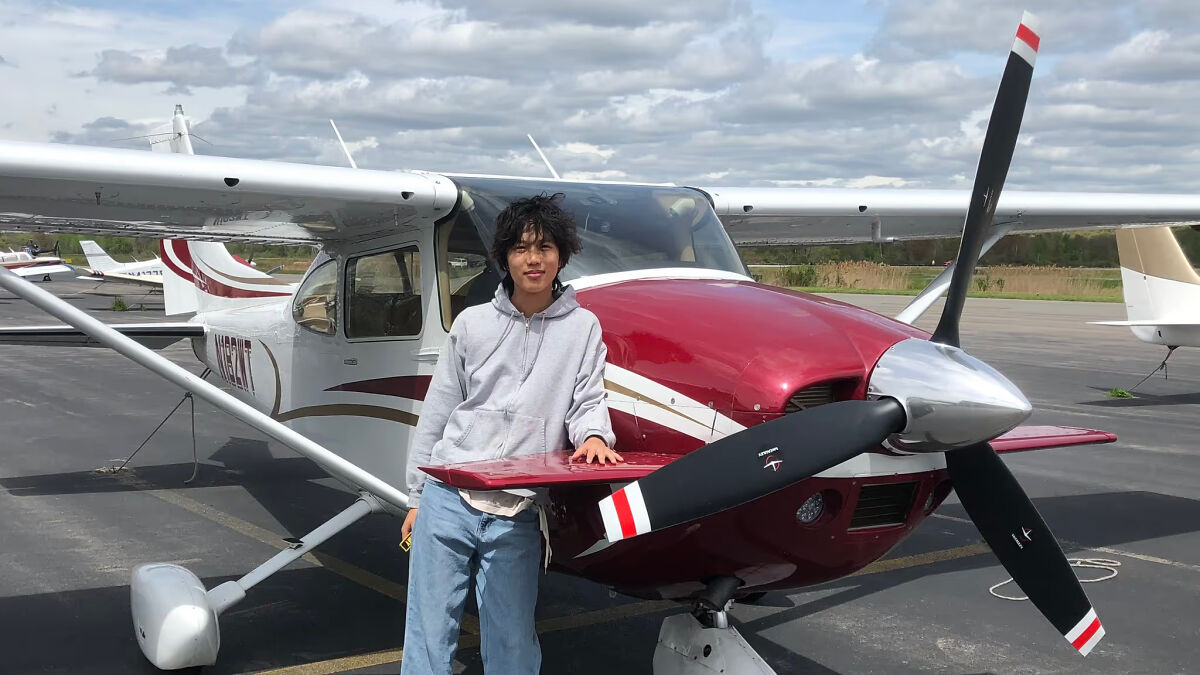 US teen pilot beside a small red and white plane preparing for a solo flight supporting a cancer cause across seven continents.